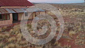 Abandoned car wreck outside an old abandoned building with rusted red roof Aerial video