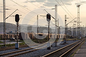 Abandoned cargo wagons on a train station, near a railway yard, at dusk, with railway signals in front, in an industrial freight l