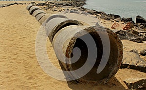 Abandoned cement pips on the beach sand.