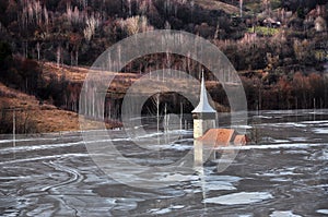 Abandoned church in a mud lake. Natural mining disaster with water pollution photo