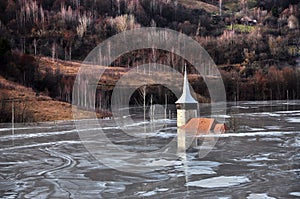 Abandoned church in a mud lake. Natural mining disaster with water pollution