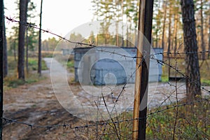 Abandoned concrete building in the forest shot through barbed wire fence