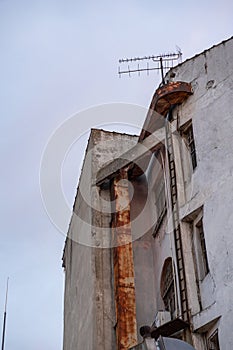 Abandoned Concrete Building with Rusty Metal Chimney and Old Antenna