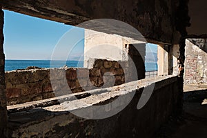 An abandoned concrete building on shores of beautiful blue sea awaiting demolition. Environmental impact. Coastal law