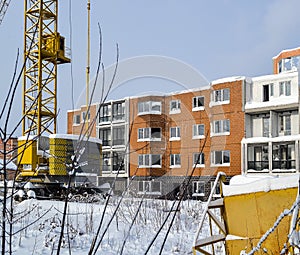 Abandoned construction of a multi-storey building. Tower crane, and a house with broken glass. Winter. Russia