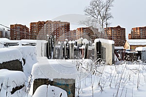 Abandoned construction of a multi-storey building. Tower crane, and a house with broken glass. Winter. Russia