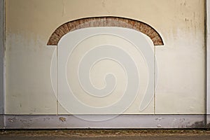 Abandoned cracked stucco brick wall with arch frame background.