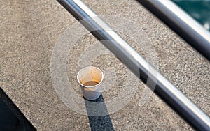 An abandoned cup of coffee on concrete as a symbol of unreasonable consumption