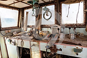 Abandoned and demolished cargo ship bridge inside view with throttle levers, communication devices and equipment