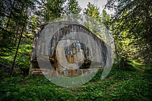 Abandoned, destoyed concrete bunker with embrasure in summer forest