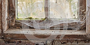 Abandoned, dirty and dusty window covered in spiderwebs in empty house from poverty and economic crisis. Old, damaged