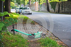 Abandoned electric scooter lies on the side of the road. Selective focus with blurred background