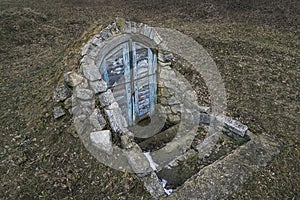 Abandoned entrance door to dungeon or basement. Perspective view of closed peeled wooden doors cellar in ground