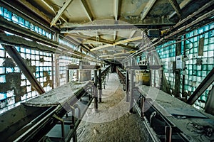 Abandoned factory. Old dusty conveyor belt in old corridor of glass brick