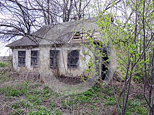 Abandoned farmhouse with broken door in the overgrown garden