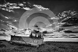 Abandoned fishing boat on beach black and white landscape at sun