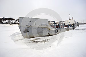 Abandoned fishing boat in a frozen river.