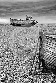 Abandoned fishing boats on shingle beach landscape in Winter