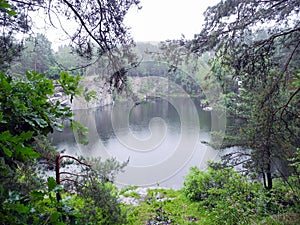 Abandoned flooded quarry in the forest. Lake in the forest. Geological outcrops