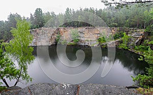 Abandoned flooded quarry in the forest. Lake in the forest. Geological outcrops