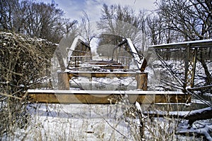A long abandoned bridge rusts under the winter snow and dreary sky photo