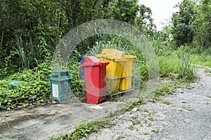 Abandoned garbage bin beside street background. Deserted trash can in the forest park