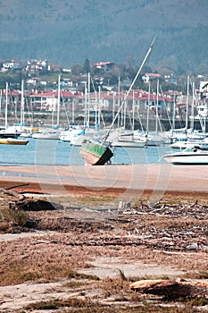 Abandoned green boat in the port of Hendaye France at low tide