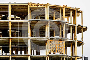 Abandoned half built new building steel structure frame with for sale sign