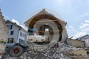 Abandoned house being demolished with mobile walking excavator and rubble and rocks