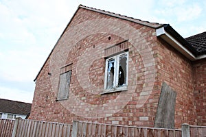 Abandoned house with a boarded up window and a smashed window UK