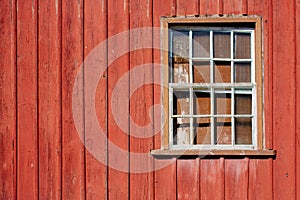 Abandoned house facade with old peeling red wooden wall and grunge broken glass window