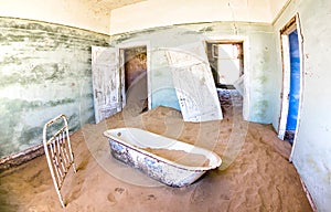 Abandoned house full of sand from the desert in the forsaken ghost town of Kolmanskop near Luderitz in Namibia photo
