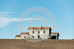 Abandoned house on the hill. Brick building covered with red tiles, broken windows and doors.