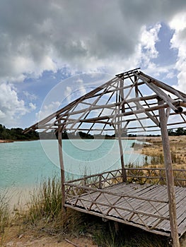 An abandoned hut on the edge of a former bauxite mining lake that is filled with water and blends with white sand