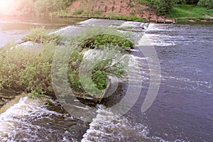 Abandoned hydroelectric power station on river waterfall with streaming current.