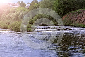 Abandoned hydroelectric power station on river waterfall with streaming current.