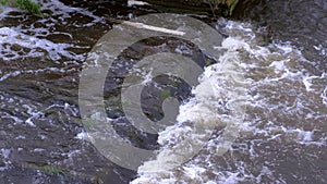 Abandoned hydroelectric power station on river waterfall with streaming current.