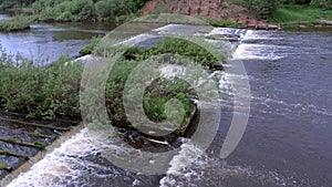 Abandoned hydroelectric power station on river waterfall with streaming current.