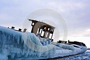 Abandoned iced barge on the shore of frozen lake