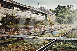 Abandoned Industrial Building On Background Of Railway Stretching Into The Distance