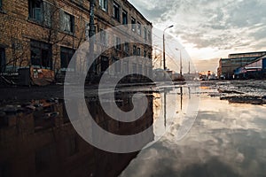 Abandoned industrial buildings reflected in pool of rainwater