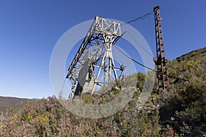 Abandoned industrial coal mining steel structure tower from cableway with cable in Tormaleo Asturias province of Spain on a bright