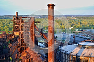 Abandoned ironworks factory - rusty chimney sunlit by the sun photo