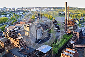 Abandoned ironworks factory with trees and city in the background