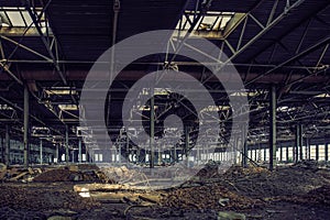 Abandoned large industrial hall or warehouse with garbage, ruined factory