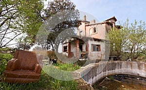 Abandoned leather armchair next to a ruined house and a pool without water