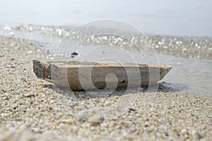 Abandoned lonely old toy wooden boat stands on the beach. Closeup