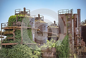 Abandoned machines and storage units in a gas industry at gas works park Seattle showing vine growth