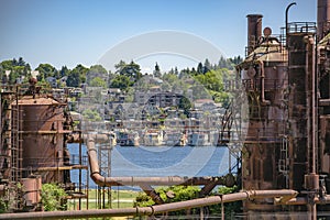 Abandoned machines and storage units in a gas industry at gas works park Seattle with water and homes