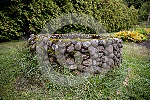 An abandoned masonry well stands in an old garden.
